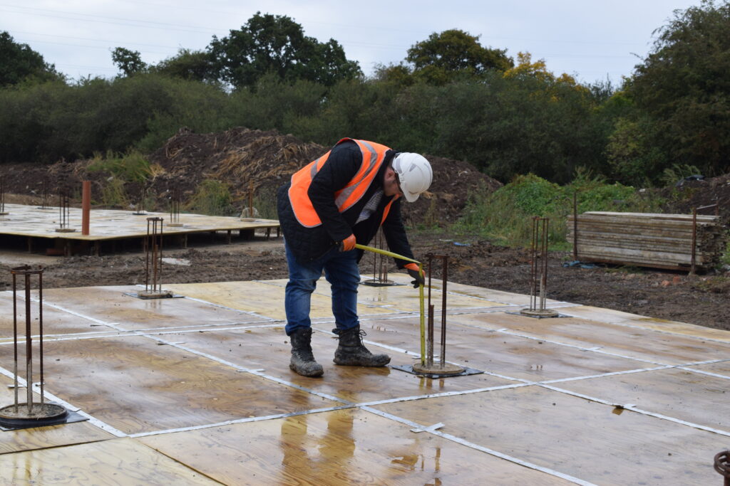 Bottom driven steel cased piles. Workman measuring the piles